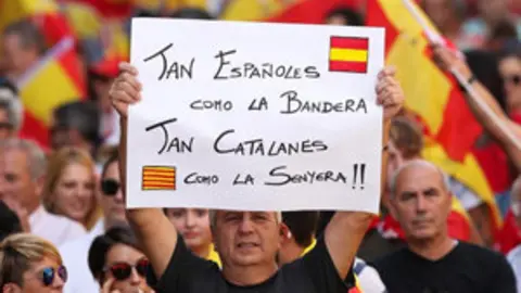 A man holds up a sign which reads  As Spanish as the flag  As Catalan as the Catalan flag  while attending a pro-union demonstration organised by the Catalan Civil Society organisation in Barcelona  Spain  October 8  2017  REUTERS Albert Gea